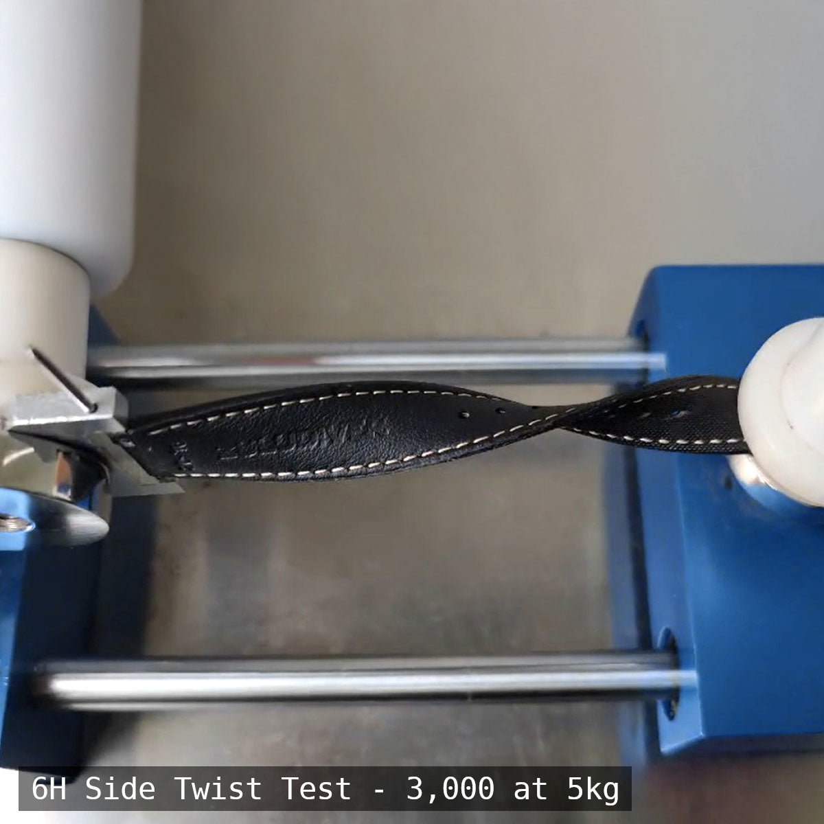 Leather strap undergoing a side twist test with testing equipment.