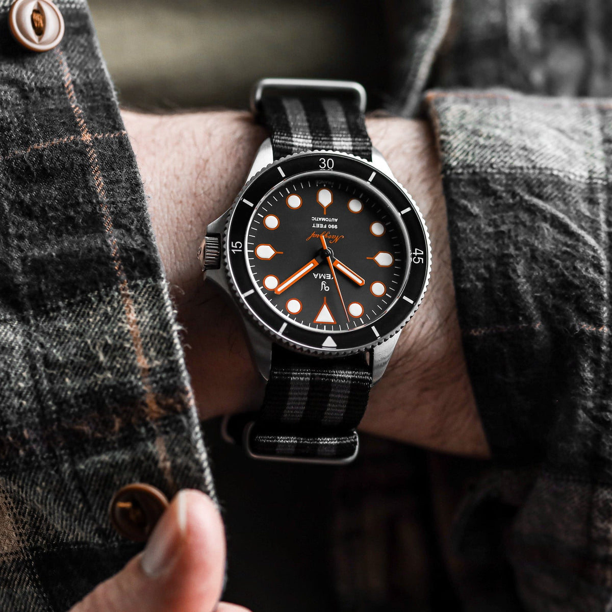 Wrist shot of classic James Bond NATO watch strap black and grey stripe, satin hardware fitted to Yema watch