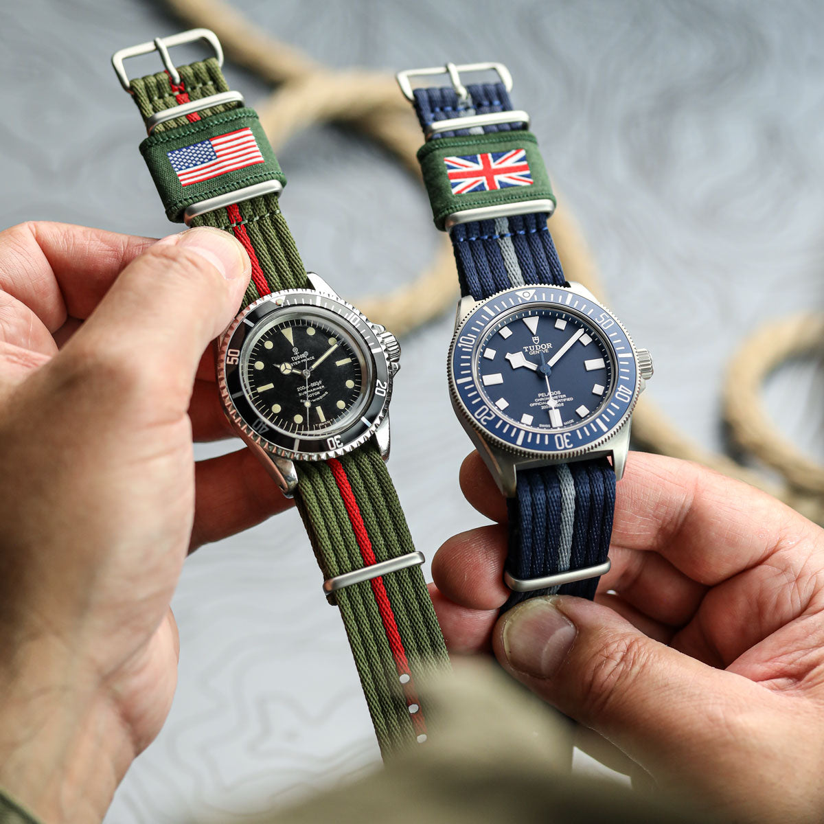 A vintage tudor watch and a new Tudor Pelegos fitted to a 1973 British Military watch strap held in a persons hand