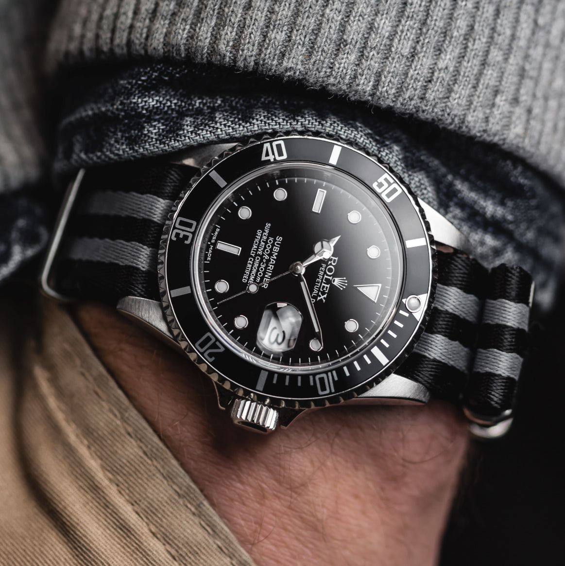 Rolex Submariner fittted to a Classic Bond military watch strap on a persons hand in their pocket