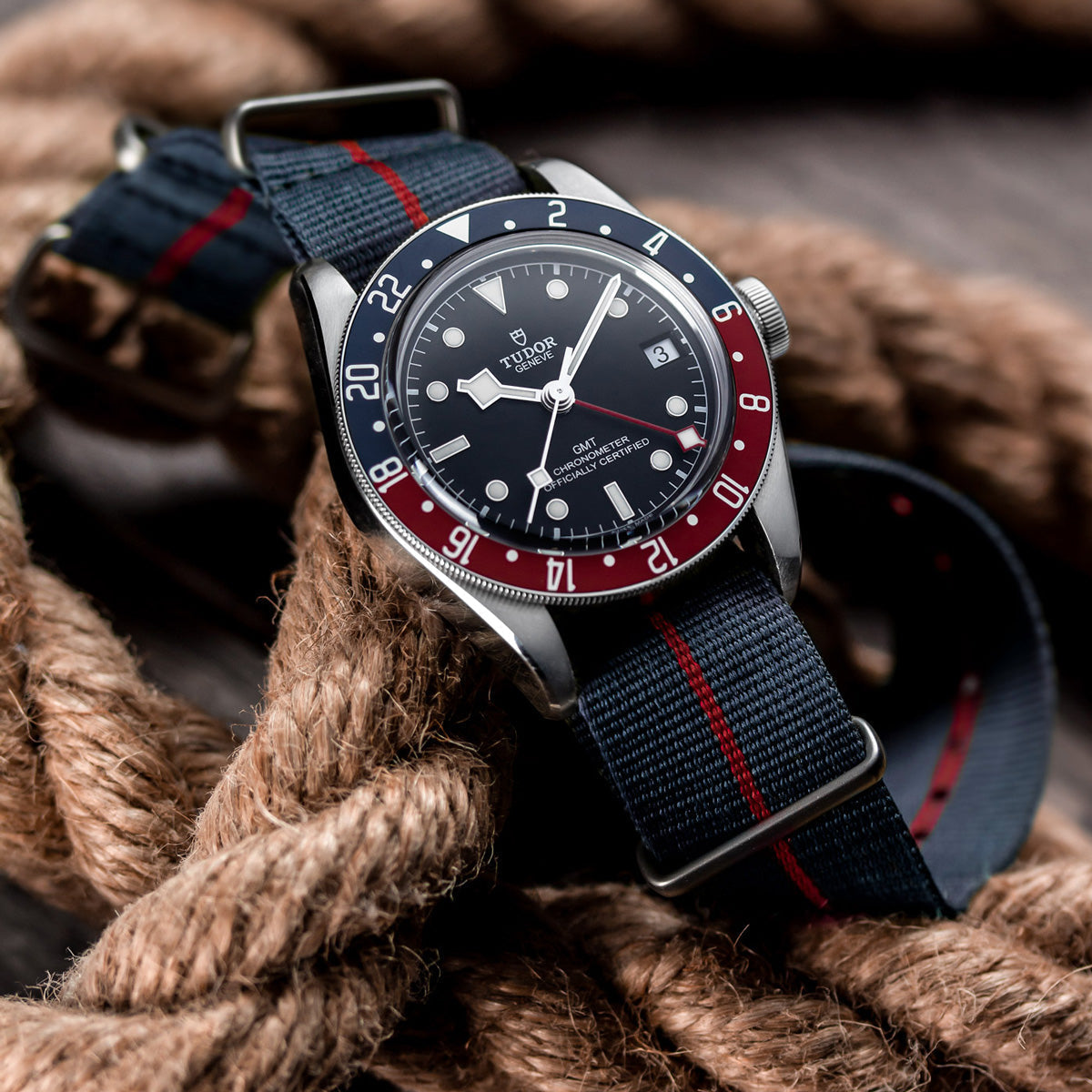 Marine National NATO Watch Strap, blue with red stripe, fitted to a Tudor Watch, sat on an old rope