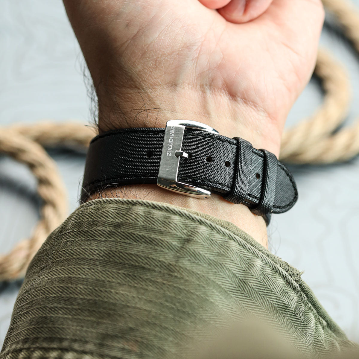 Black watch strap on a wrist with a blurred background