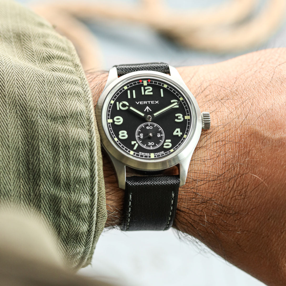 Vertex watch on a person&#39;s wrist with a blurred background, fitted to Maverick sailcloth watch strap with grey stitching