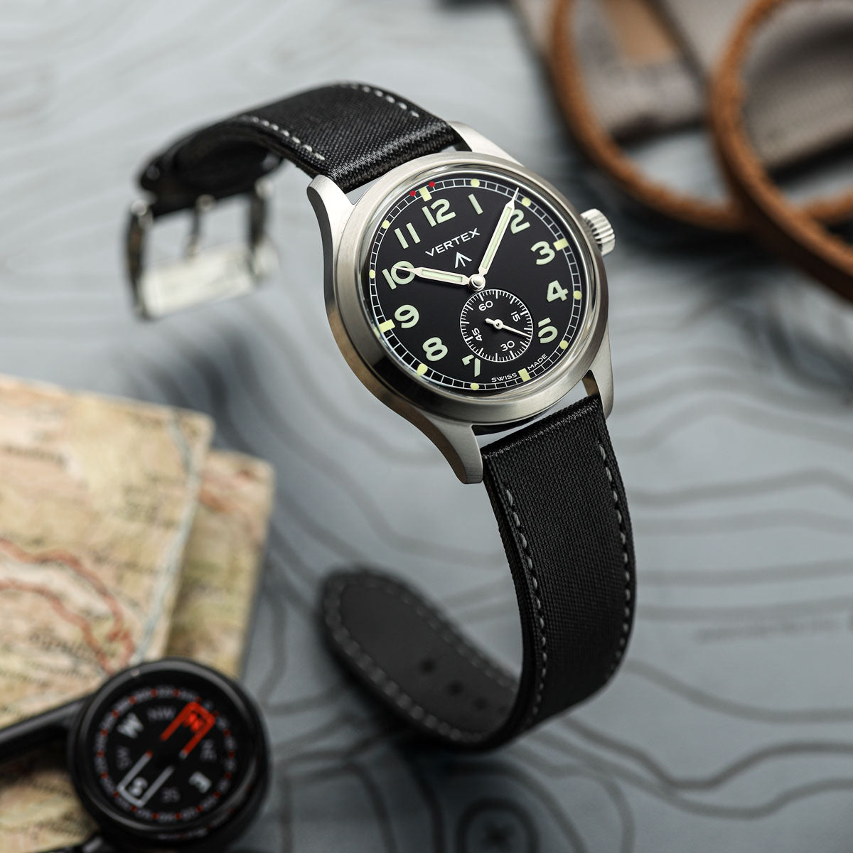 Vertex Watch with black strap on a textured surface with map and compass